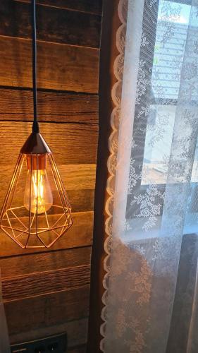 a light hanging from a wooden wall with a window at B&B Plitvice Holiday Lodge in Plitvička Jezera