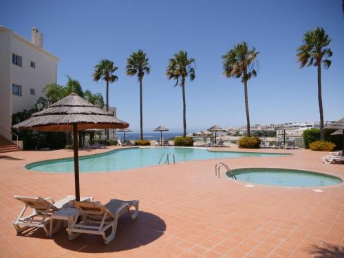a swimming pool with two lounge chairs and an umbrella at Large Penthouse Near Porto de Mos Beach With Magnificent Views In Lagos in Lagos