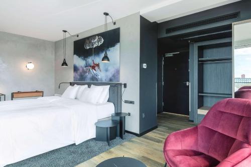 a bedroom with a white bed and two chairs at Radisson RED Aarhus in Aarhus