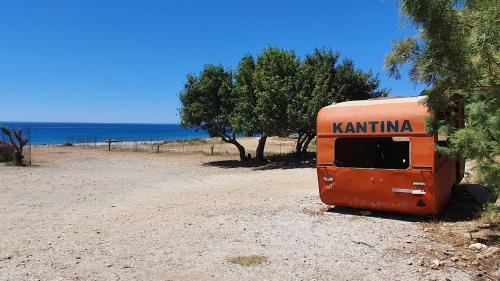 an orange trailer parked on a dirt road near the ocean at Galini Breeze in Agia Galini