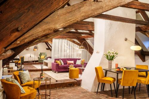 a living room with wooden ceilings and yellow chairs at Bellevue Hotel Český Krumlov in Český Krumlov