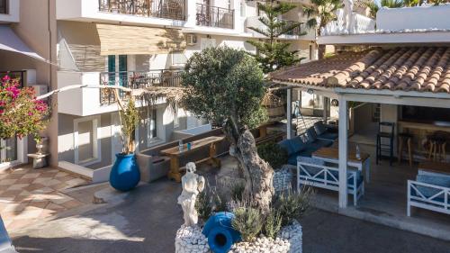 an apartment building with a courtyard with benches and trees at Iniohos Zante Hotel & Suites in Argasi