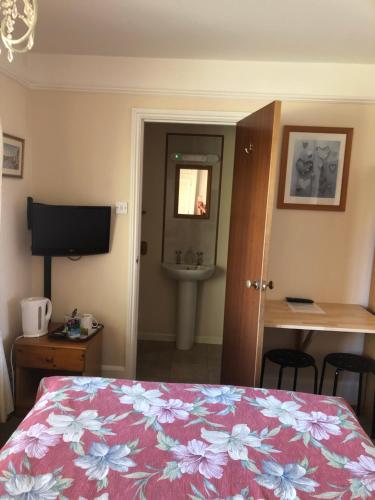 1 dormitorio con 1 cama y baño con lavamanos en Auplands en-suite Rooms, en Lymington