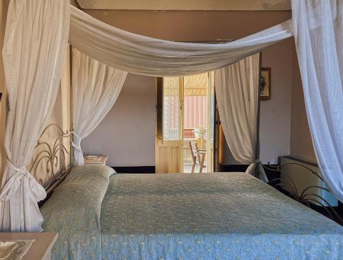 ein Schlafzimmer mit einem großen Bett mit Vorhängen in der Unterkunft Palazzo Gambuzza in Ispica