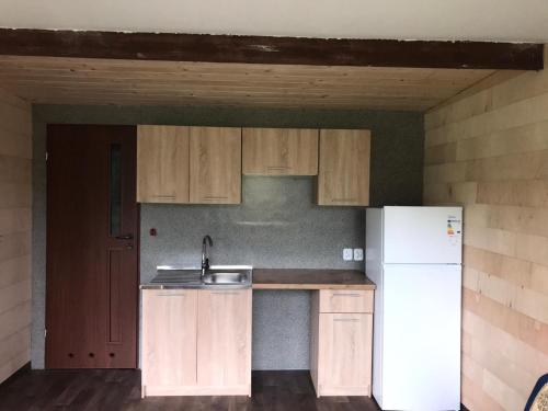 eine Küche mit Holzschränken und einem weißen Kühlschrank in der Unterkunft Domek letniskowy na Mazurach nad stawem in Gromoty