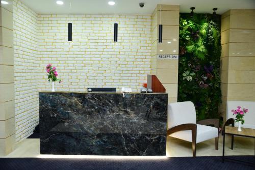 a lobby with a black marble counter and chairs at Hotel Comfort in Tirana