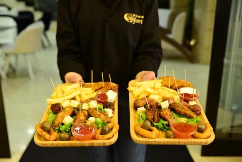 a man holding two trays of food with french fries at Hotel Comfort in Tirana