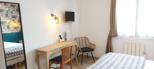 a room with a desk and two chairs and a bed at Logis Hôtel Vannes Nord Le Clos Des Hortensias in Locqueltas
