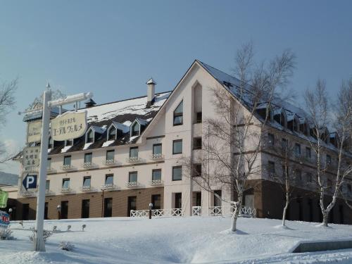 a building in the snow in front at Hotel Edel Warme in Furano