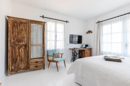 a bedroom with a bed and a wooden cabinet and a chair at Deniz Kabugu Hotel in Alacati