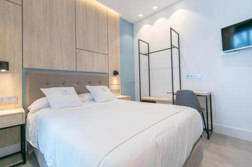 ein Schlafzimmer mit einem großen weißen Bett und einem TV in der Unterkunft Real Maqueda - Málaga in Málaga
