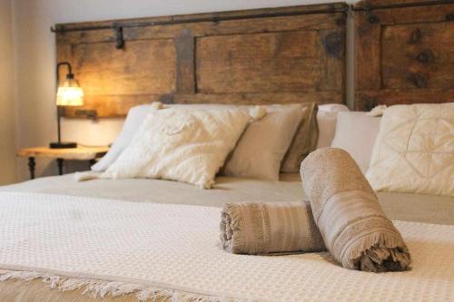 1 cama blanca grande con cabecero de madera y almohadas en Casa El Tío Carrascón alojamiento rural, en Cerveruela