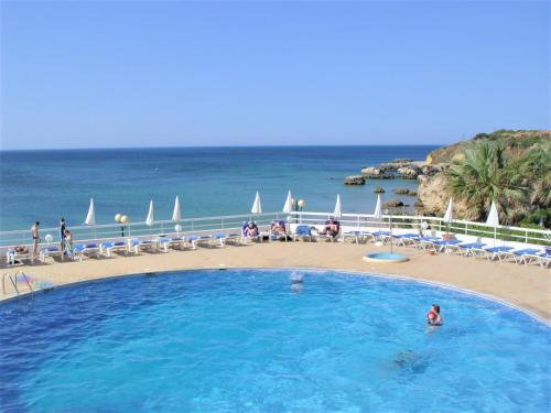 a large swimming pool with a beach and the ocean at Apartamentos Borda D´Agua in Albufeira
