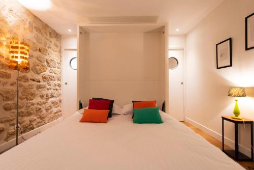 巴黎的住宿－Popy，卧室配有一张带彩色枕头的大型白色床。