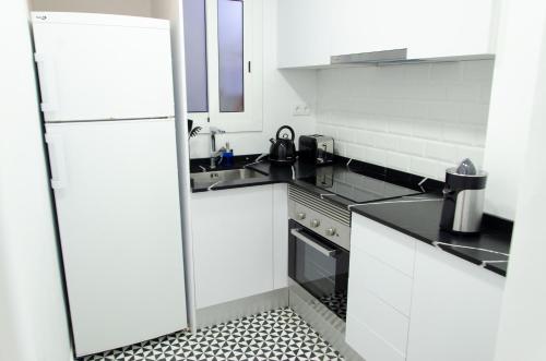 a white kitchen with a refrigerator and a sink at Apartamento NUEVO con encanto en SAGRADA FAMILIA in Barcelona