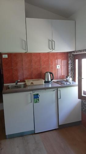 una cocina con armarios blancos y fregadero en Guest house Sara, en Rijeka