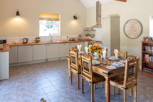 cocina con mesa de madera y sillas en The Coal House en Kidwelly