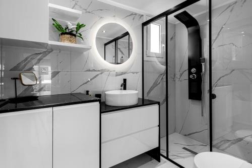 a white bathroom with a sink and a mirror at Diogenis Seaside Suite in Rethymno Town