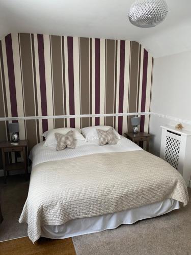 a bedroom with a large white bed with striped walls at Ship Stores Guest House in Clare