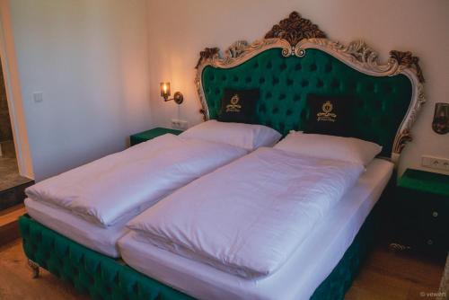two beds in a bedroom with a green headboard at Innviertler Versailles in Aurolzmünster