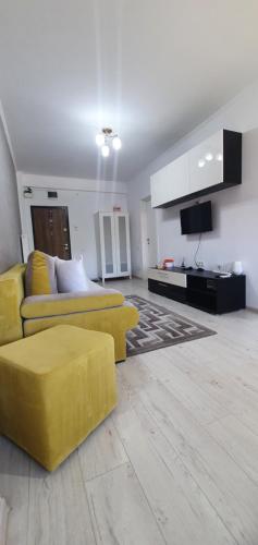 a living room with a yellow couch and a tv at Sarah Apartment in Constanţa