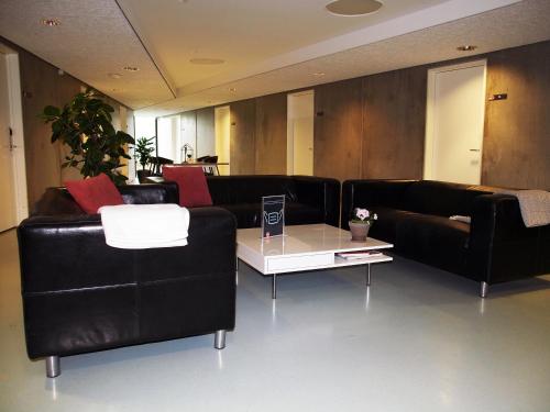 a living room with black leather couches and a coffee table at DBU Hotel & Kursuscenter in Aarhus