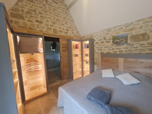 sypialnia z łóżkiem i kamienną ścianą w obiekcie Moulin du soustre w mieście Cavagnac