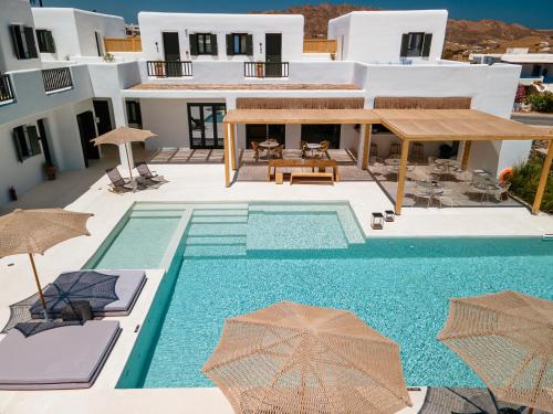 a pool with chairs and umbrellas next to a house at Koukoumi Vegan Boutique Hotel in Ano Mera