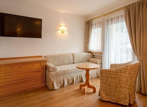 una sala de estar con un sofá y una mesa en Hotel Villa Eden, en Corvara in Badia