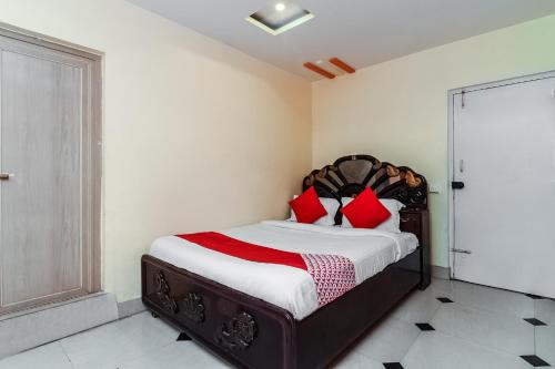 - une chambre avec un lit et des oreillers rouges dans l'établissement OYO Sindhura Guest House, à Raspari Palao