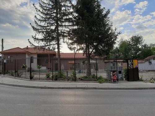 a fence on the side of a street with a tree at Квартири ЦЕНТРАЛ in Dolna Mitropoliya