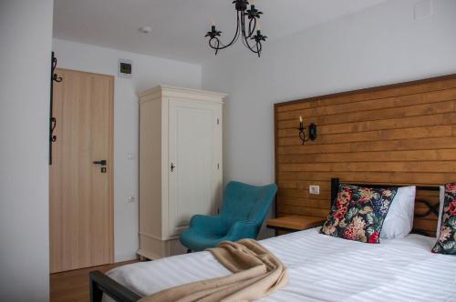 a bedroom with a bed and a blue chair at Chalet Mugure de Brad in Fundu Moldovei
