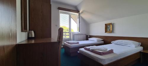 een kamer met 2 bedden, een bureau en een raam bij Guest House Tiha noć in Žabljak