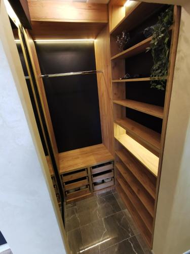 a walk in pantry with wooden cabinets and a refrigerator at Brend new luxurious apartment in downtown with free parking in Novi Sad