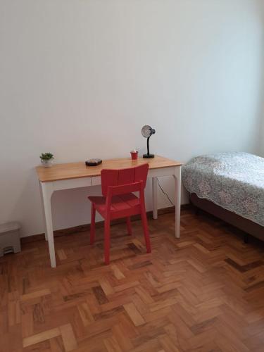 a desk with a red chair next to a bed at Pousada Monte Alegre in Sao Paulo