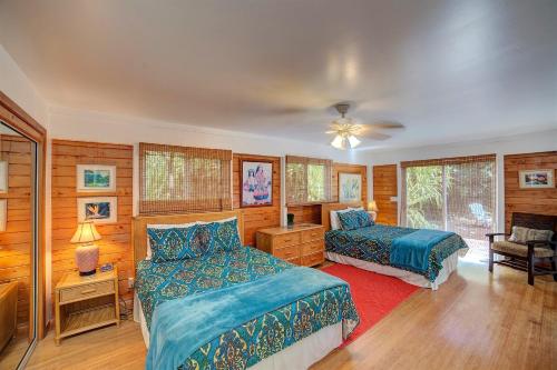 two beds in a bedroom with wooden walls at Hale Ki'i Maka Manu home in Keaau