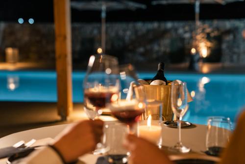 a table with two glasses of wine and candles at Koukoumi Vegan Boutique Hotel in Ano Mera