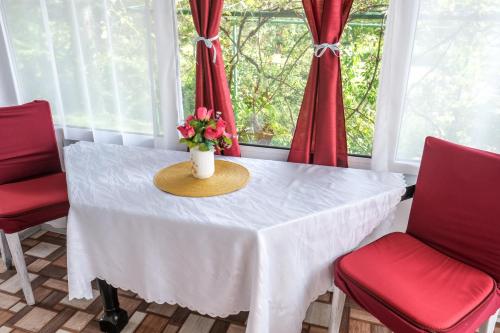 une table avec des chaises rouges et un vase avec des fleurs. dans l'établissement Ruralna kuća za odmor LOVRAK, à Budrovac