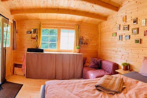 a room with a bed and a couch in a cabin at Nature retreat in a beautiful off-grid cabin in Rouge