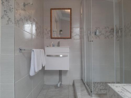 La salle de bains blanche est pourvue d'un lavabo et d'une douche. dans l'établissement Lesedi Self Catering, à Pretoria