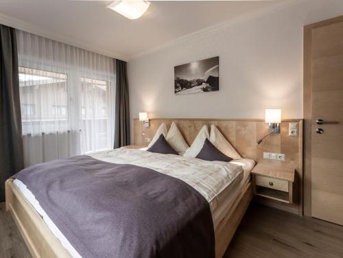 a bedroom with a large bed and a window at FRAU GANS - pure mountain apartments in Saalbach Hinterglemm