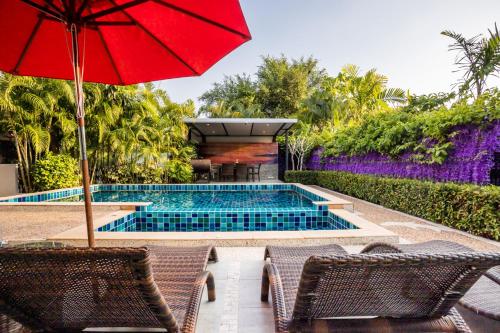 a pool with two chairs and a red umbrella at 3 Bedroom Exclusive Private Pool Villa Smooth as Silk in Ao Nang Beach