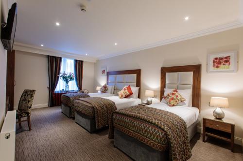 a hotel room with two beds and two chairs at Grand Hotel Tralee in Tralee