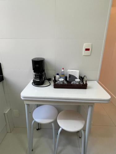 uma mesa branca com 2 cadeiras e comodidades para preparar café em Point de Ipanema - 2 quartos no Rio de Janeiro