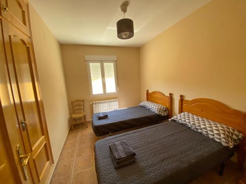 1 dormitorio con 2 camas y ventana en El Rincón de Dorotea - Casa rural, en Villalba de la Sierra