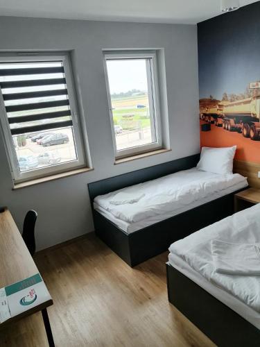 two beds in a room with two windows at blue hotel in Kalisz