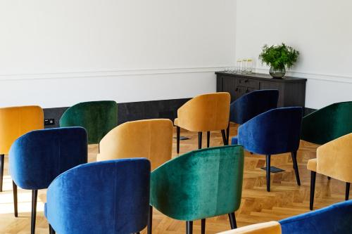 a room with blue and green chairs in a classroom at Hotel Liberte 33 BW Premier Collection in Poznań