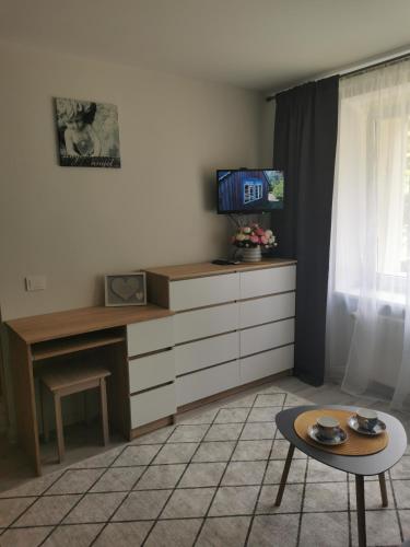 a living room with a table and a tv on a desk at Upės apartamentai in Biržai