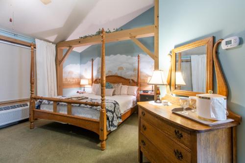 um quarto com uma cama de dossel e uma cómoda em madeira em The Barn Inn Bed and Breakfast em Millersburg