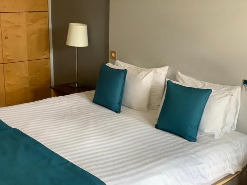 a large bed with two blue pillows on it at The Angel Hotel in Cardiff